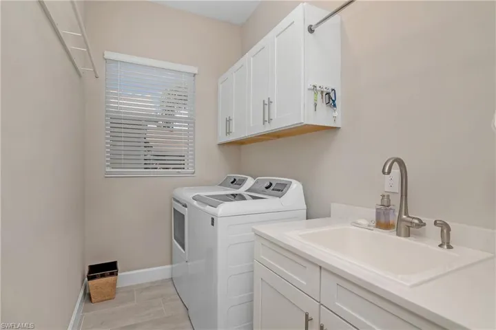 Spacious and bright laundry room with utility sink and additional cabinetry for storage.