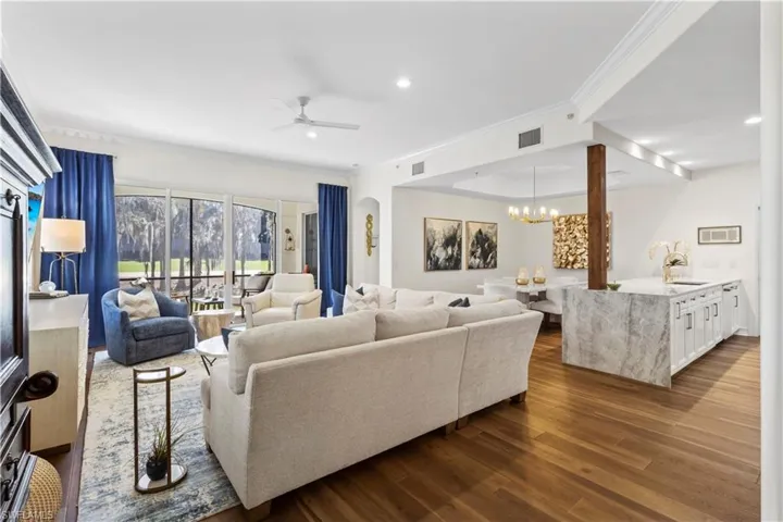 Living area featuring ornamental molding, dark wood finished floors, ceiling fan, and hanging lights