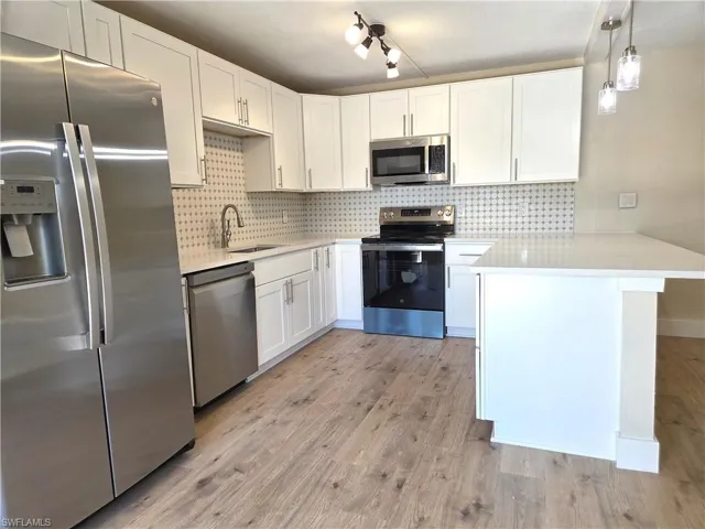 Modern kitchen with white cabinetry and light-toned wood-finish flooring
