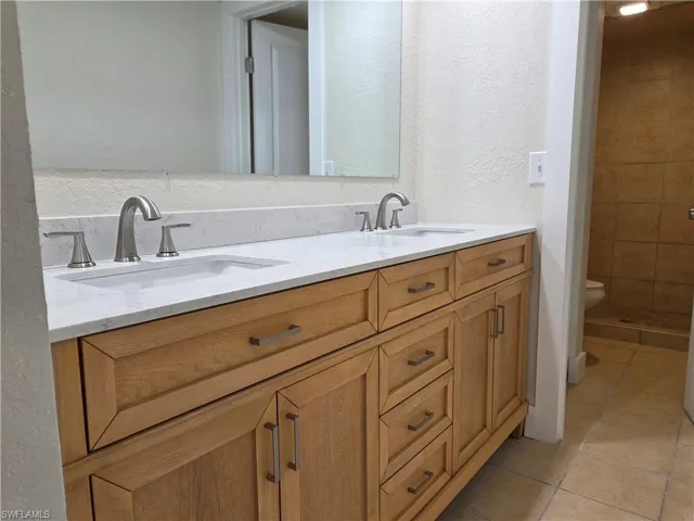 Double vanity featuring light wood cabinetry and brushed nickel hardware