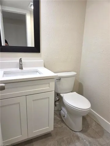 Bathroom vanity with a white countertop and integrated sink, brushed nickel faucet, and a large framed mirror
