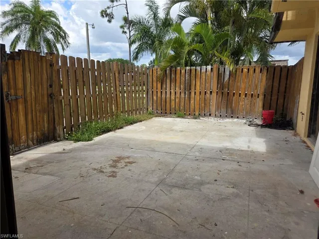 Paved concrete patio featuring a perimeter wood fence with a gate