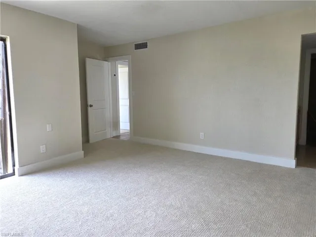 Bright interior room featuring neutral-toned walls, white baseboards, and light-colored carpeting