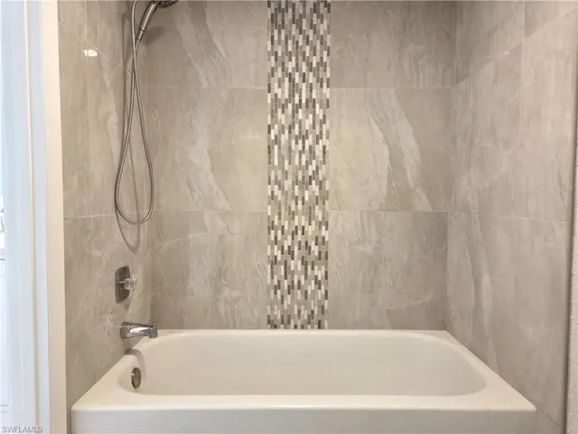 Bathtub with a multi-tone mosaic tile accent wall