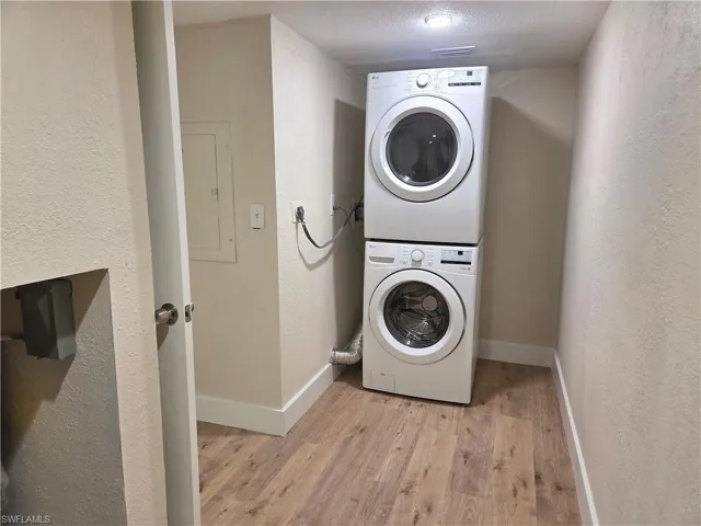 Dedicated laundry area featuring wood-finish flooring and a stackable washer and dryer