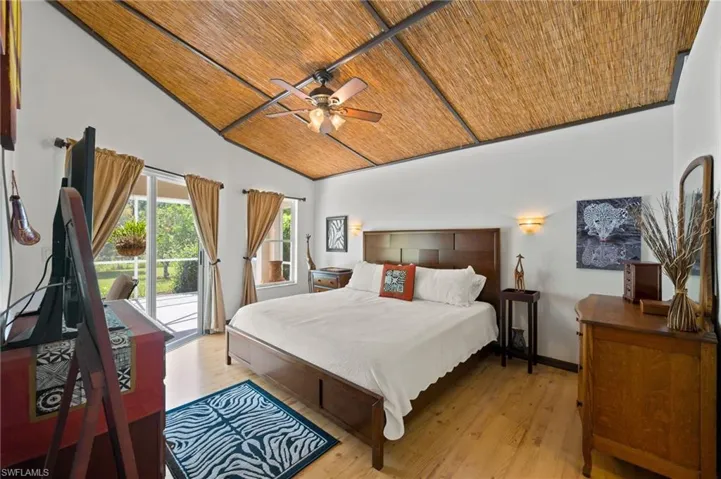 Primary Bedroom featuring wood-style flooring, vaultd ceiling and sliders to Lanai.  Ceiling is coverd with light babo style wood that can be easily removed.
