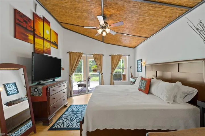 Primary Bedroom with slider to lanai, vaulted ceiling, and light colored wood-style floors