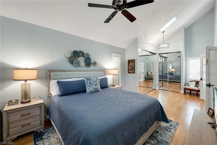 Bedroom featuring ceiling fan, a skylight, high vaulted ceiling, and light hardwood / wood-style flooring