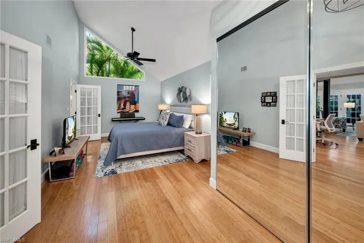 Bedroom with ceiling fan, french doors, high vaulted ceiling, and hardwood / wood-style flooring