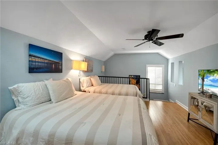 Bedroom featuring ceiling fan, wood-type flooring, and vaulted ceiling