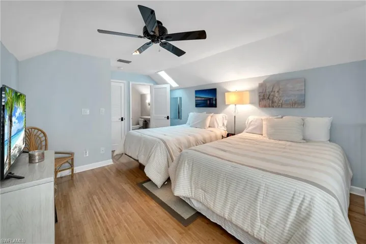 Bedroom with ceiling fan, light hardwood / wood-style floors, and lofted ceiling