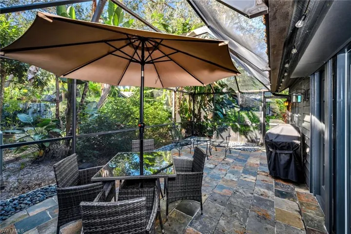 View of patio featuring glass enclosure and a grill