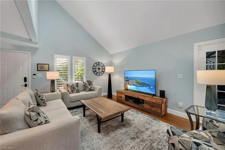 Living room with hardwood / wood-style flooring and high vaulted ceiling