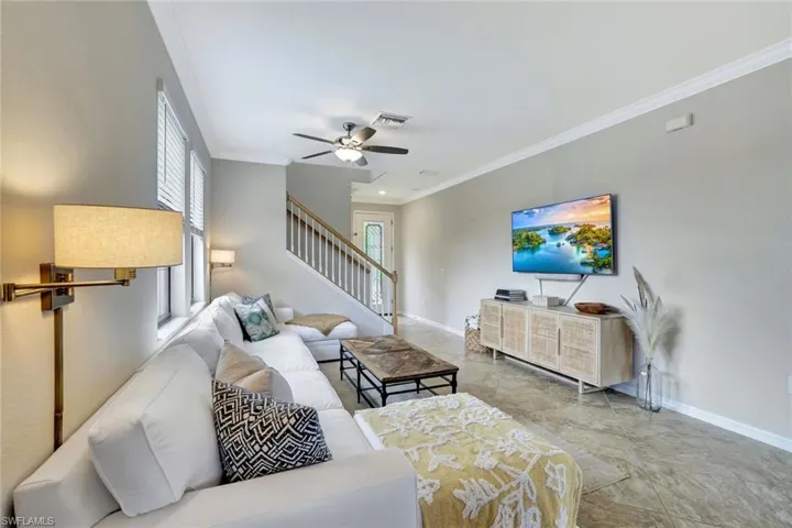 Living room featuring ceiling fan, a healthy amount of sunlight, crown molding and tile floors.