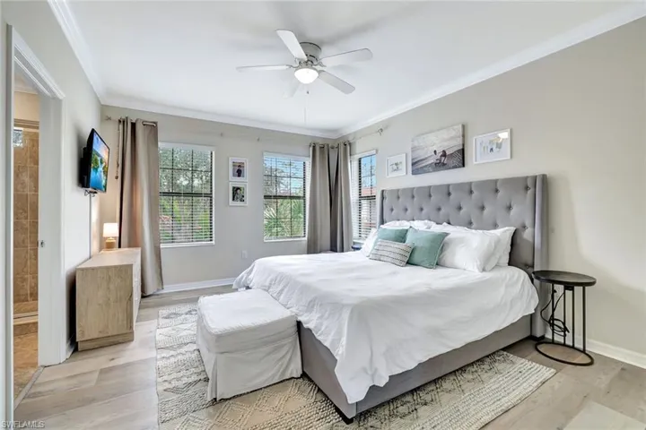 Large Primary bedroom with crown molding, ceiling fan, plenty of natural light, a walk in closet and an ensuite bathroom.