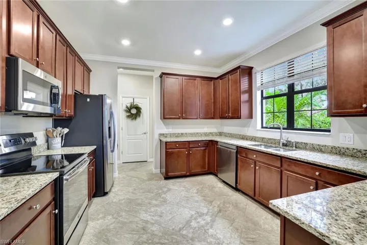 Kitchen with crown molding, granite countertops, stainless steel appliances and a pantry.