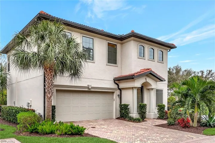 Mediterranean style home featuring a paver driveway, 2 car attached garage and beautiful landscaping