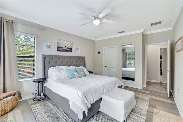 Large Primary bedroom with crown molding, ceiling fan, plenty of natural light, a walk in closet and an ensuite bathroom.