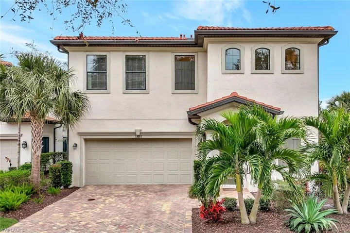 Mediterranean style home featuring a paver driveway, 2 car attached garage and beautiful landscaping