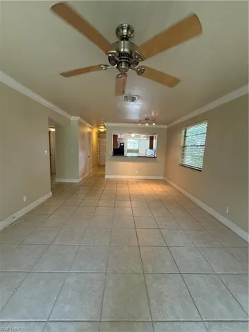 Unfurnished room with ornamental molding, light tile patterned flooring, and ceiling fan