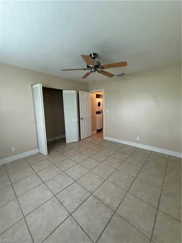 Unfurnished bedroom featuring washer / dryer, a closet, light tile patterned floors, and a ceiling fan