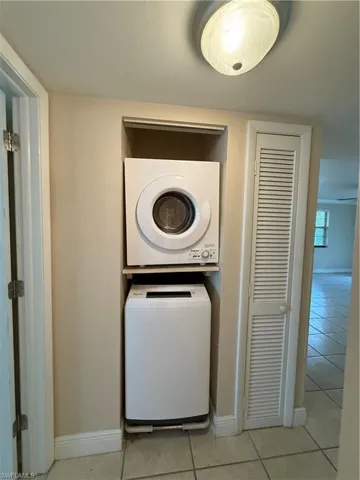 Laundry area featuring estacked washer and dryer and light tile patterned floors