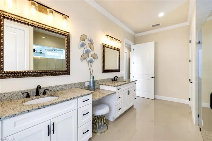 Full bath with a stall shower, crown molding, two vanities, double vanity, and recessed lighting