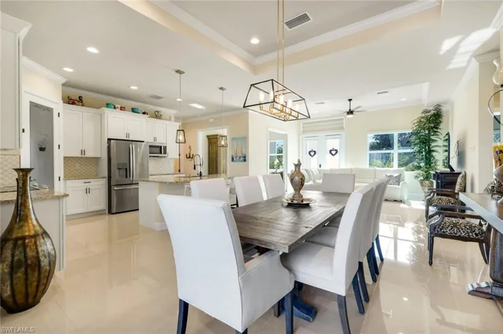 Dining space with crown molding, a tray ceiling, recessed lighting, light tile patterned flooring, and a chandelier