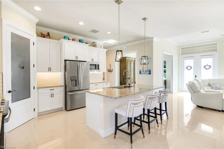 Kitchen featuring open floor plan, tasteful backsplash, a breakfast bar, stainless steel appliances, and crown molding