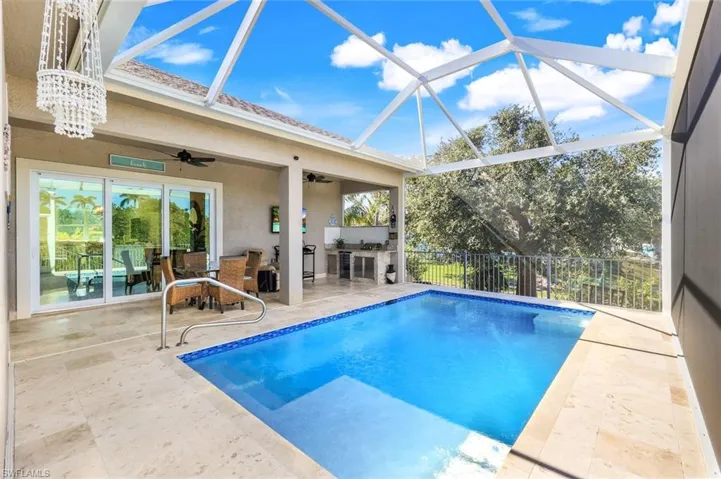 Swimming pool with a sunroom, a patio, ceiling fan, a lanai, and an outdoor kitchen
