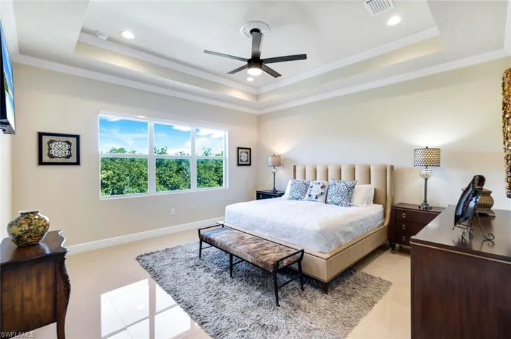 Bedroom featuring a tray ceiling, crown molding, ceiling fan, recessed lighting, and light tile patterned floors