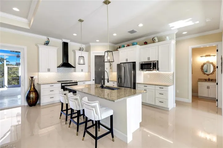 Kitchen featuring crown molding, a breakfast bar, white cabinets, appliances with stainless steel finishes, and light stone counters