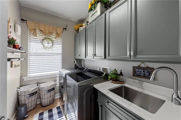 Laundry area with separate washer and dryer, cabinet space, and wood finished floors