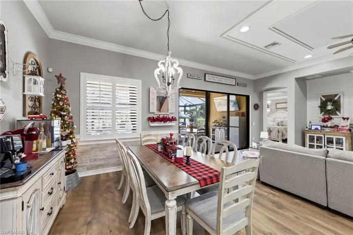 Dining space featuring healthy amount of natural light, wood finished floors, ornamental molding, wainscoting, and arched walkways