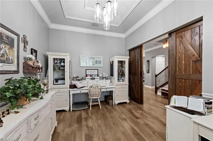 Office featuring dark wood-style floors, crown molding, a chandelier, and built in desk