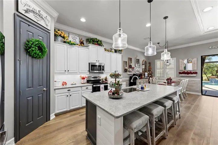 Kitchen with white cabinets, appliances with stainless steel finishes, pendant lighting, a breakfast bar, and light wood-style flooring