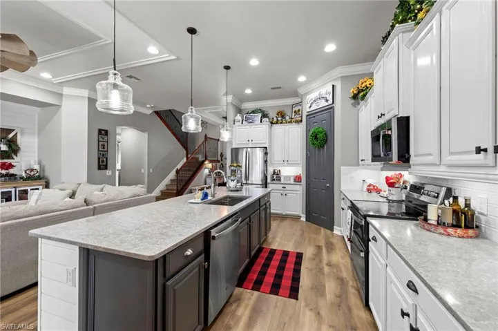 Kitchen featuring white cabinetry, stainless steel appliances, open floor plan, tasteful backsplash, and decorative light fixtures