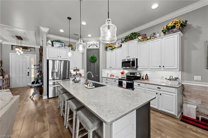 Kitchen with white cabinetry, appliances with stainless steel finishes, a kitchen bar, recessed lighting, and backsplash