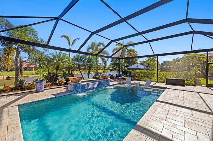 View of pool featuring glass enclosure, a sunroom, a pool with connected hot tub, and a patio