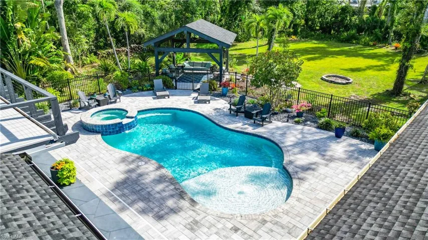 View of swimming pool with a fire pit, a patio, a pool with connected hot tub, and a fenced backyard