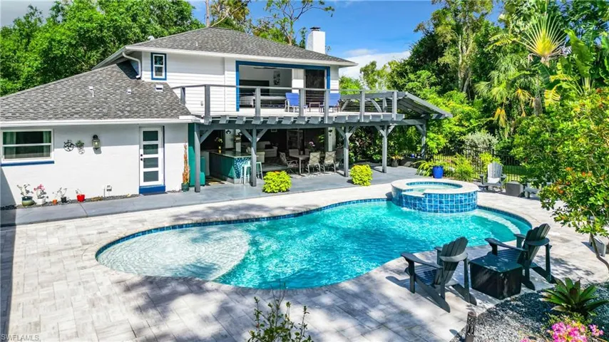Back of house featuring a patio, a pool with connected hot tub, an alumium deck, and a covered outside entertainment area