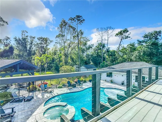 View of swimming pool with a pool with connected hot tub, view of wooded area, and a patio