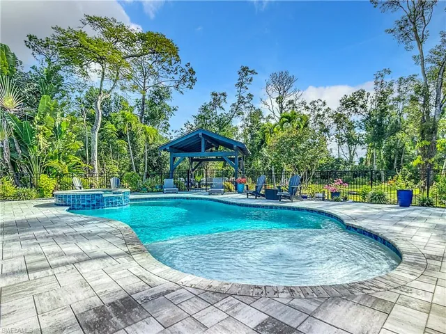 View of pool featuring a patio, a fenced backyard, and a pool with connected hot tub