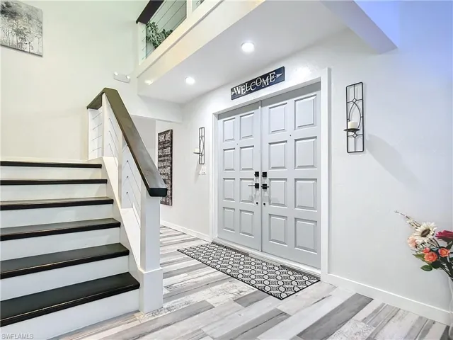 iInside entryway with light tile floors, stairs, and recessed lighting
