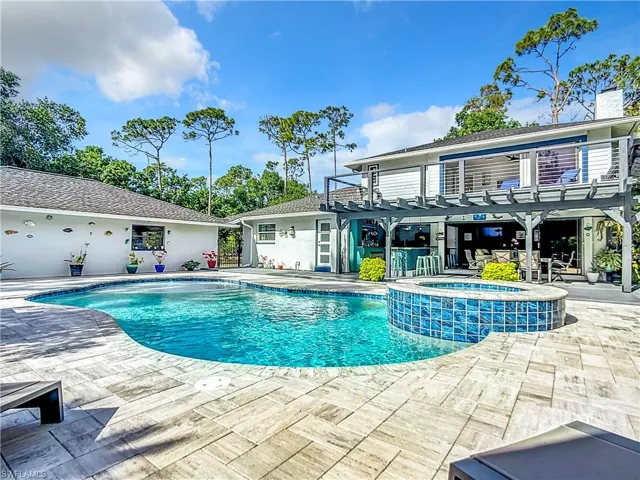 View of swimming pool featuring a pool with connected hot tub, a patio, a balcony, and a pergola