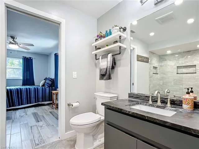 Downstairs bathroom featuring stone vanity, and a tile shower