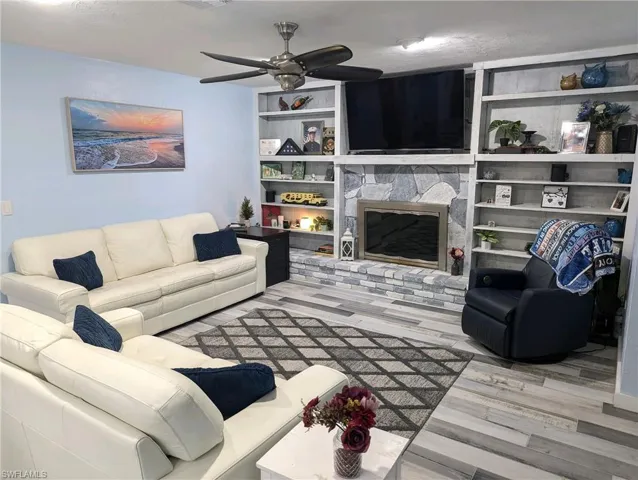 Living room with a wood burning ireplace, and a designer ceiling fan