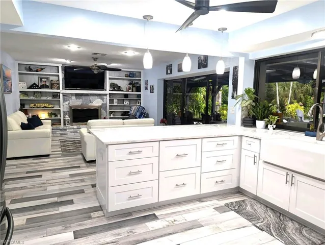 Kitchen featuring a ceiling fan, pendant light fixtures, and stone counters