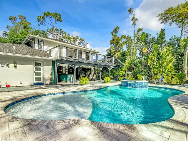 View of swimming pool featuring a pergola, a patio area, a pool with connected hot tub, and a balcony