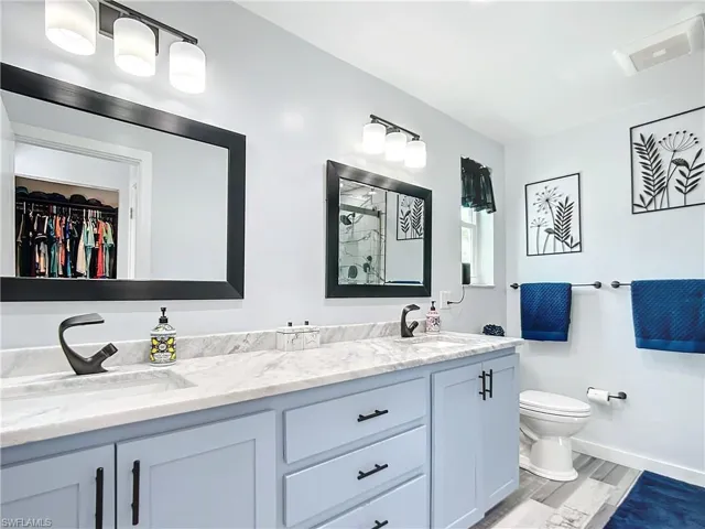 Primary Bathroom featuring a spacious linen closet, double vanity, and designer faucets